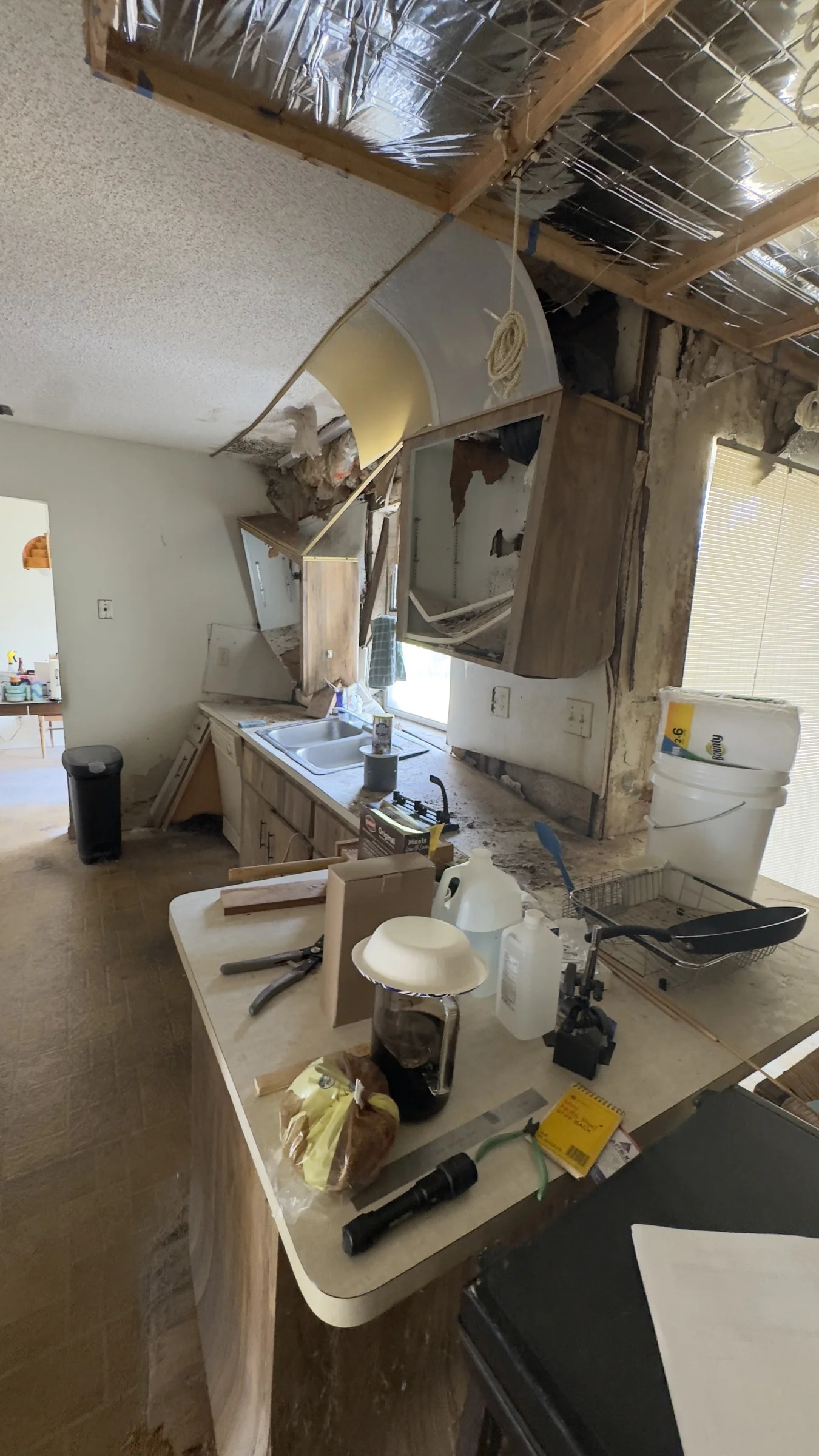 Kitchen during demolition with exposed ceiling framing and removed upper cabinets